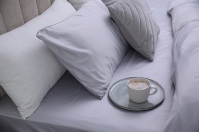 Photo of Cup of coffee on bed with soft silky bedclothes