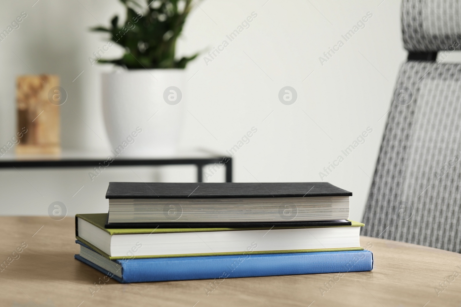 Photo of Many different books stacked on wooden table indoors