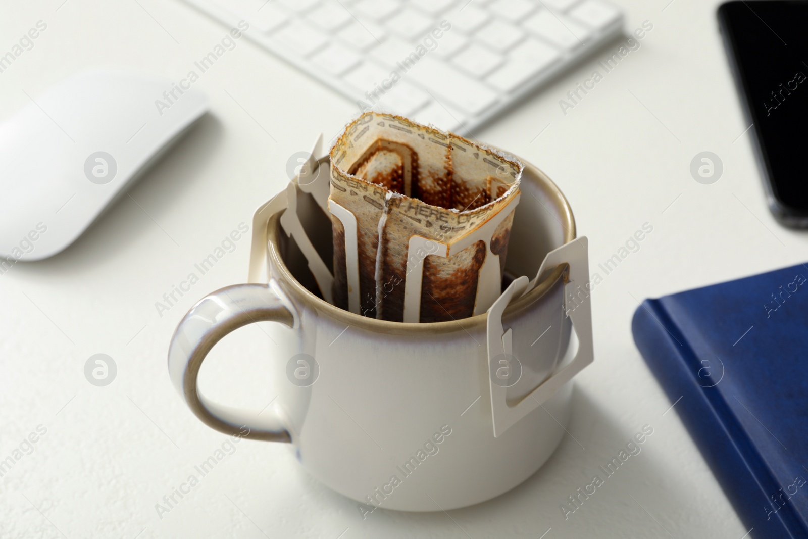 Photo of Cup with drip coffee bag on white table, closeup