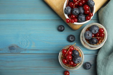 Photo of Delicious yogurt parfait with fresh berries on turquoise wooden table, flat lay. Space for text