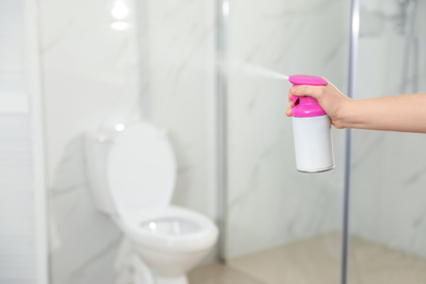 Photo of Woman spraying air freshener in bathroom, closeup