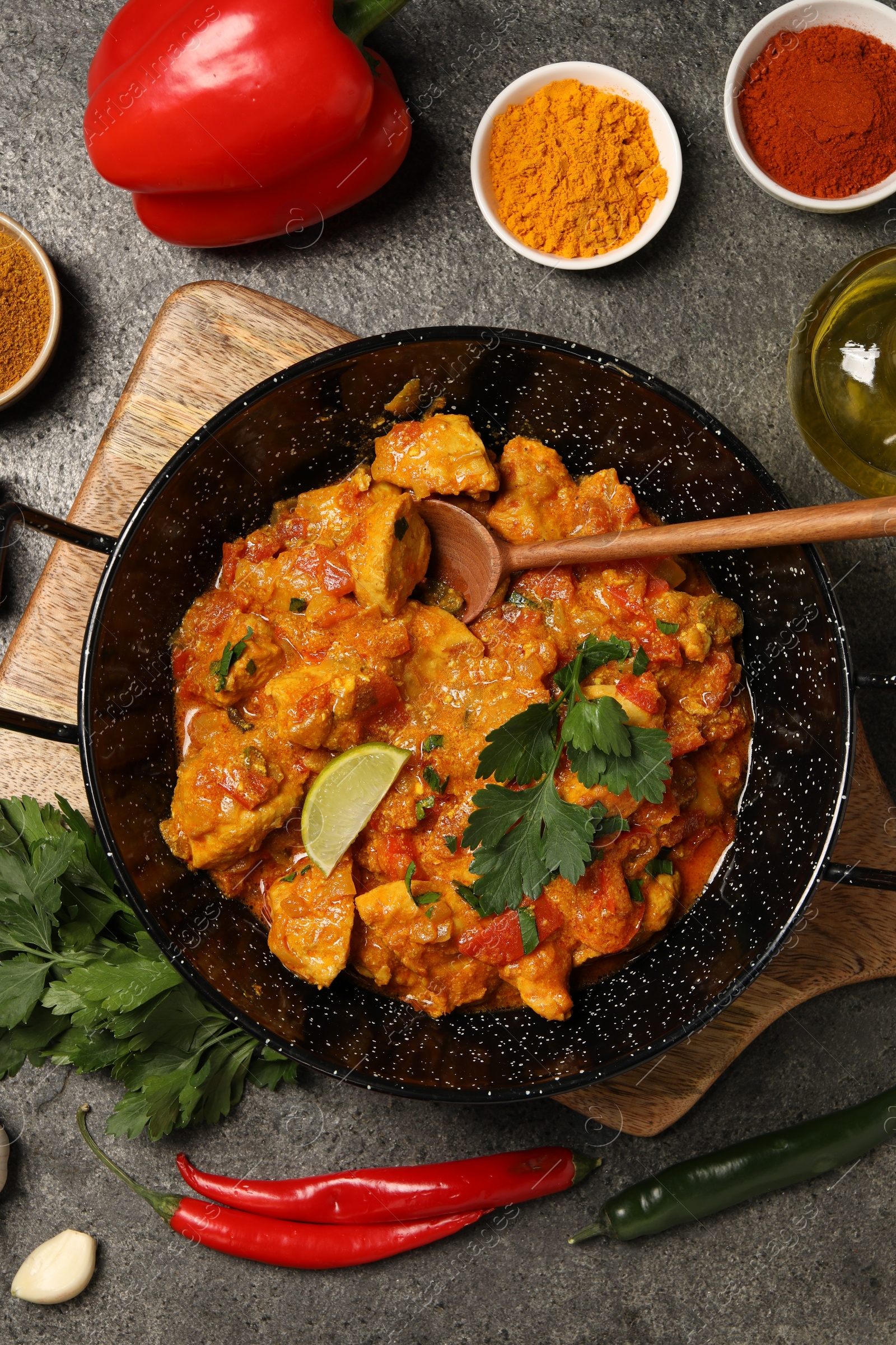 Photo of Delicious chicken curry and ingredients on grey table, flat lay