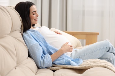 Photo of Happy pregnant woman on sofa at home