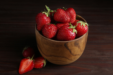 Photo of Delicious ripe strawberries in bowl on wooden table, closeup