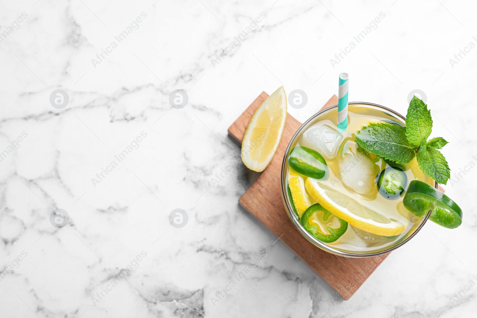 Photo of Spicy cocktail with jalapeno, lemon and mint on white marble table, top view. Space for text