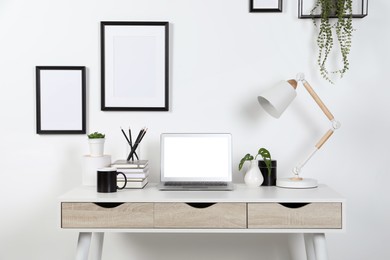 Photo of Home workplace. Laptop, lamp and stationery on white wooden desk