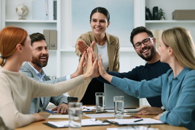 Team of employees joining hands in office