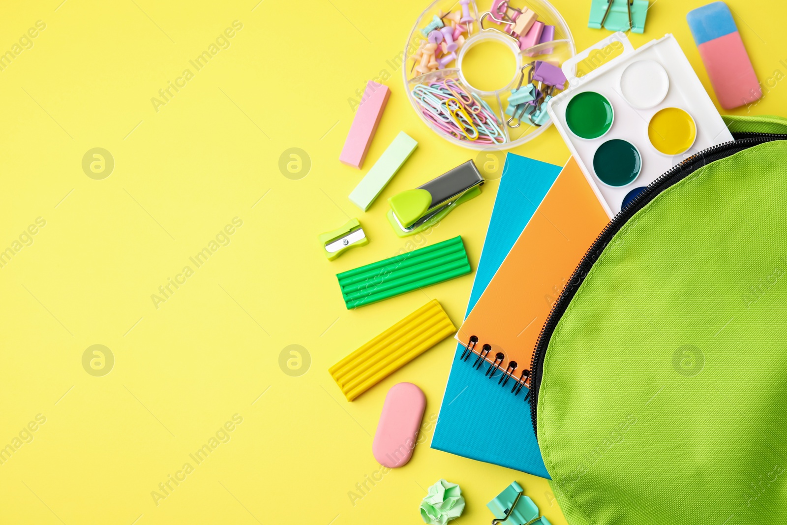 Photo of Flat lay composition with different school stationery on pale yellow background, space for text. Back to school