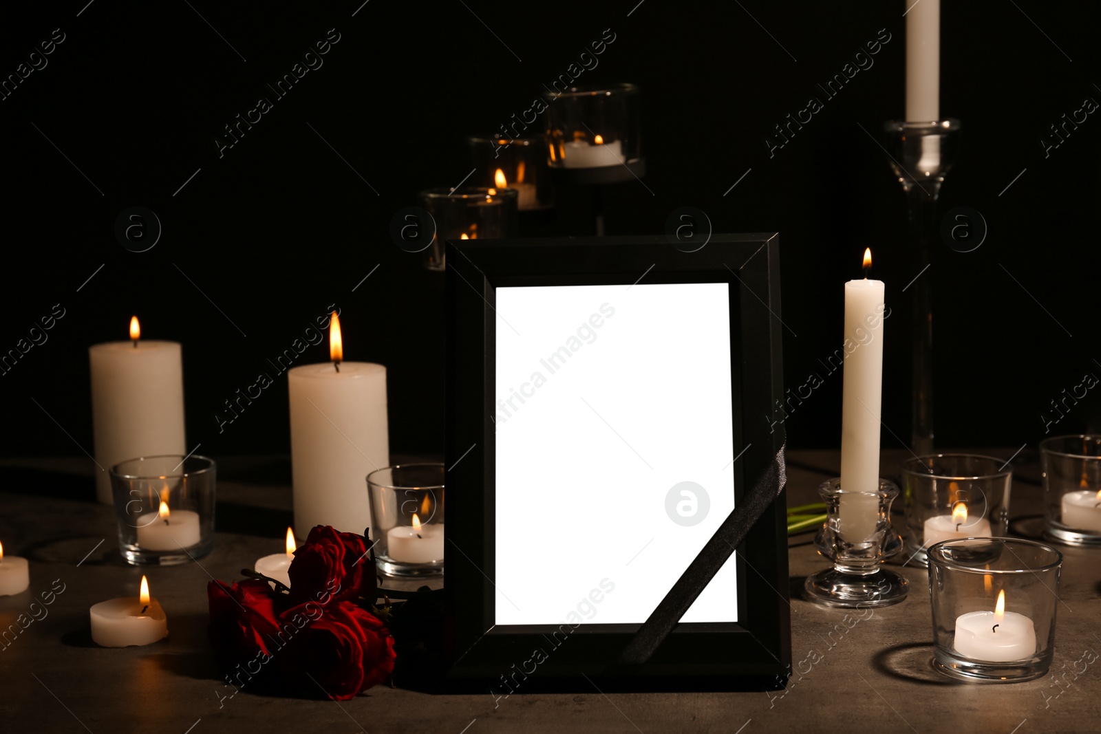 Photo of Empty frame with black ribbon, candles and roses on table. Funeral symbol