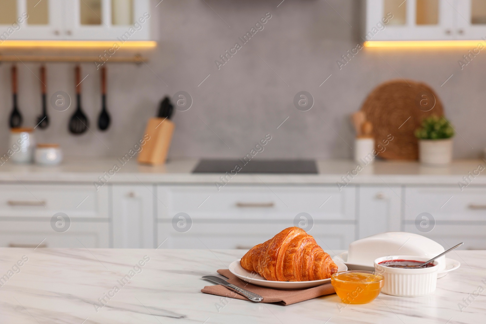 Photo of Breakfast served in kitchen. Fresh croissant, jam and honey on white table. Space for text