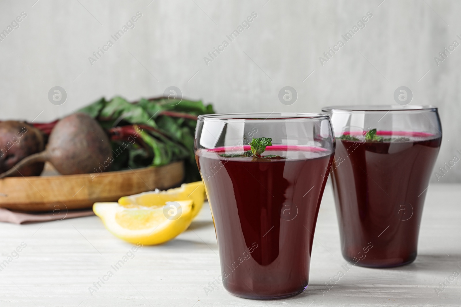 Photo of Glasses of beet juice on white wooden table. Space for text