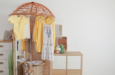 Photo of Stylish dressing room interior with wooden furniture and clothes