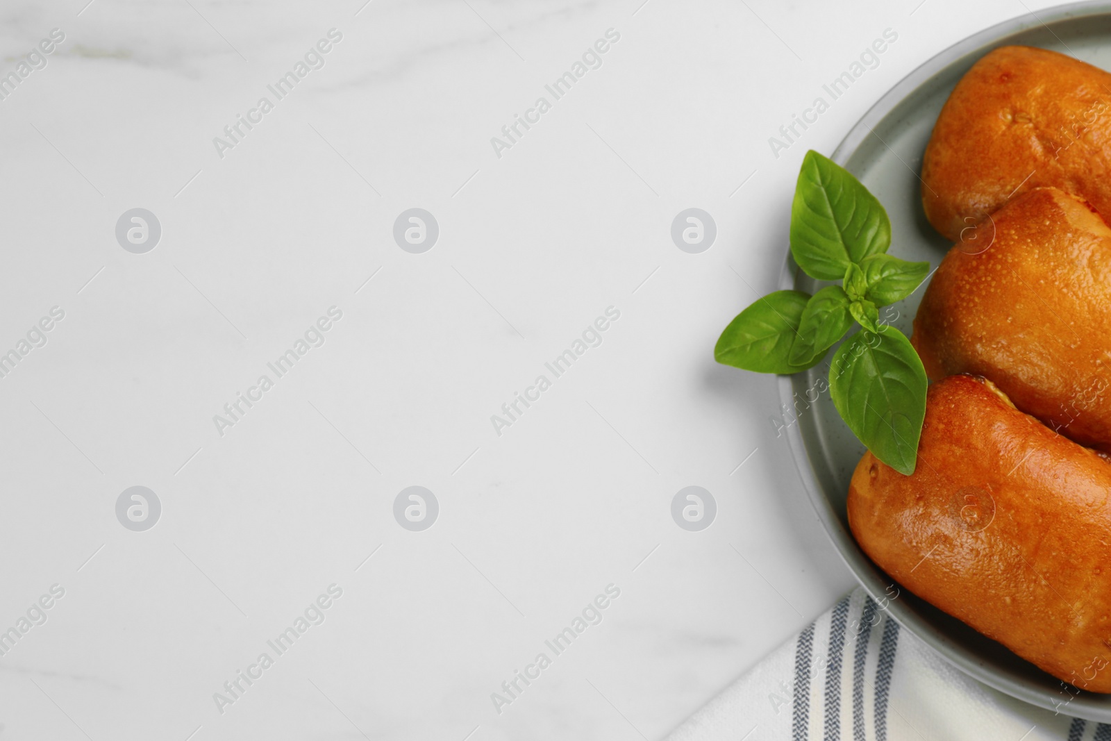 Photo of Delicious baked patties and basil on white table, top view. Space for text