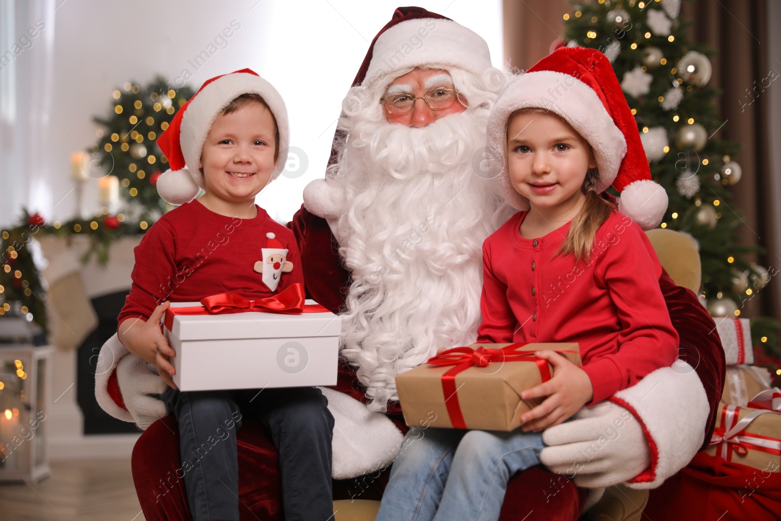 Photo of Santa Claus and little children with presents in room decorated for Christmas