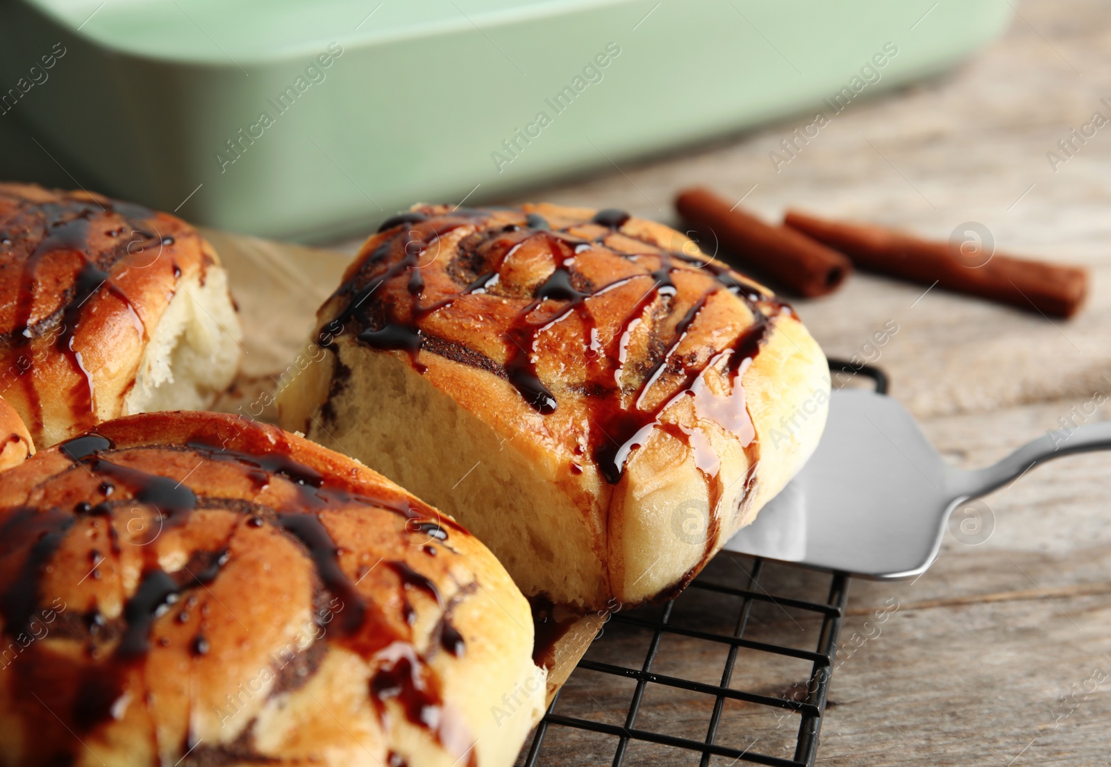 Photo of Cooling rack with freshly baked cinnamon rolls on table, closeup