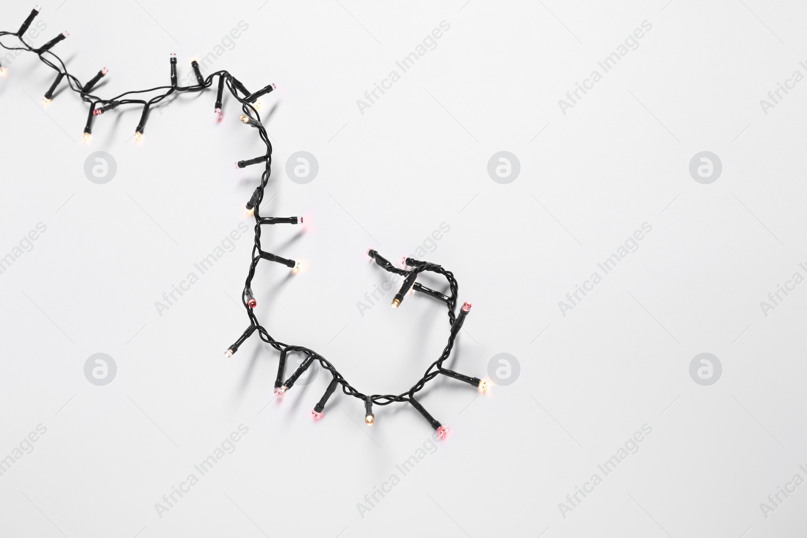 Photo of Beautiful Christmas lights on white background, top view