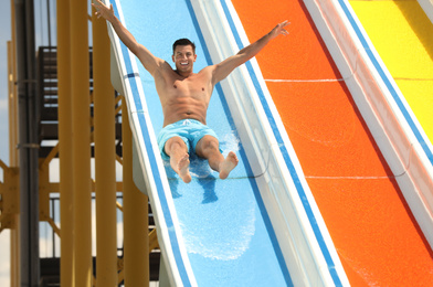 Photo of Man on slide at water park. Summer vacation