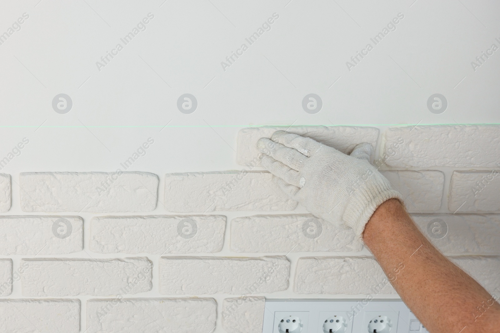 Photo of Worker installing decorative wall tiles in room, closeup