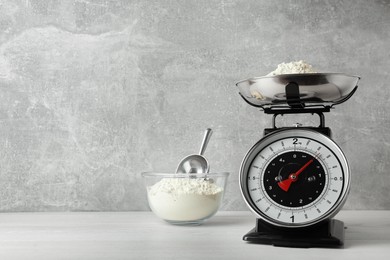 Kitchen scale with flour on white wooden table. Space for text