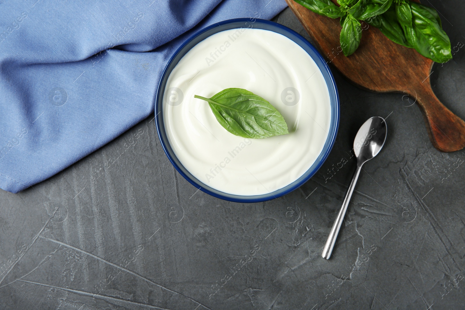 Photo of Flat lay composition of sour cream with basil on grey table