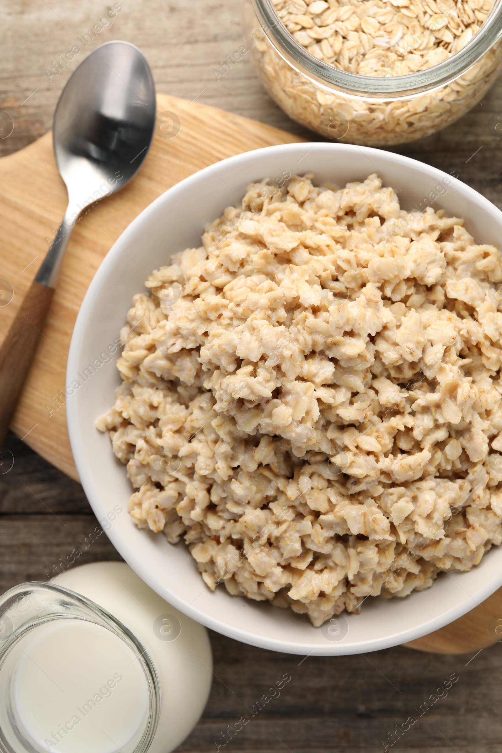Photo of Tasty boiled oatmeal served on wooden table, flat lay