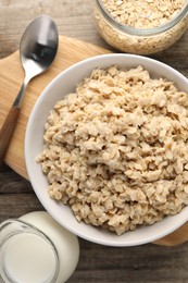 Photo of Tasty boiled oatmeal served on wooden table, flat lay