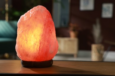 Himalayan salt lamp on wooden table indoors, space for text