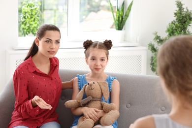 Photo of Young mother and her daughter visiting child psychologist in office