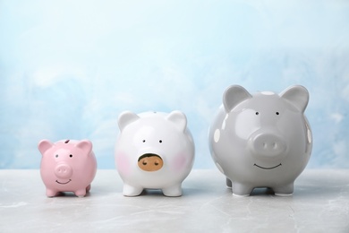 Photo of Three cute piggy banks on table against color background