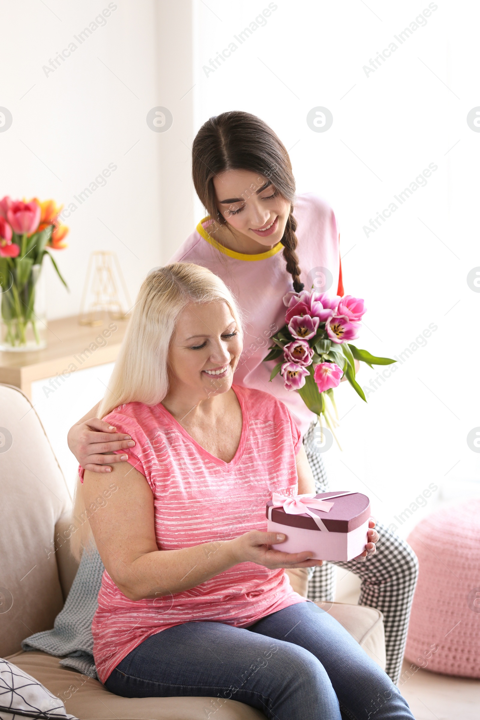 Photo of Daughter congratulating happy mature woman on Mother's Day at home