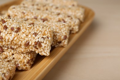 Plate with tasty sesame seed bars on wooden table, closeup