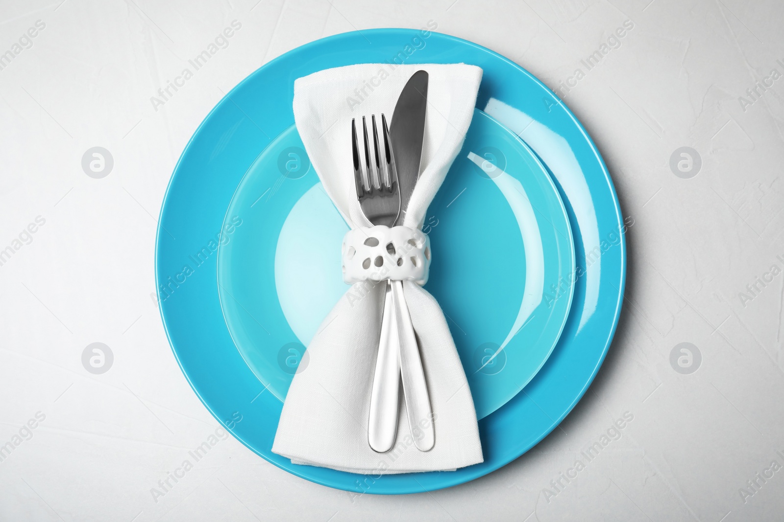 Photo of Plates with cutlery and napkin on light background, top view. Festive dinner setting