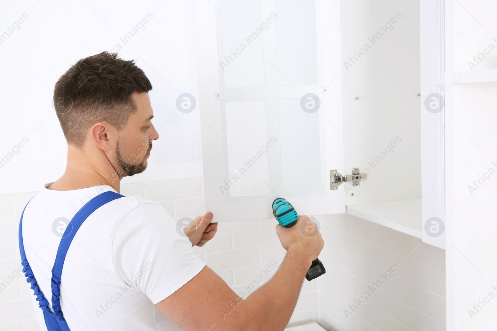 Photo of Worker installing kitchen furniture with electric screwdriver