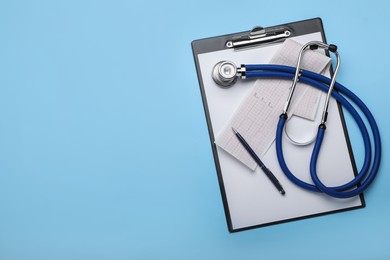 Photo of Stethoscope, clipboard and cardiogram paper on light blue background, top view. Space for text