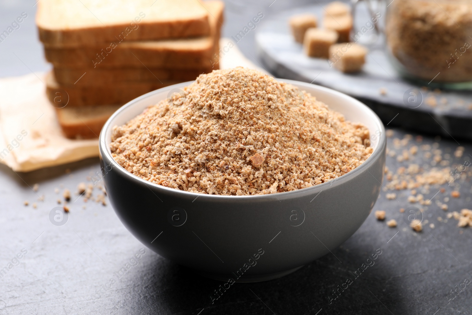 Photo of Fresh breadcrumbs in bowl on black table