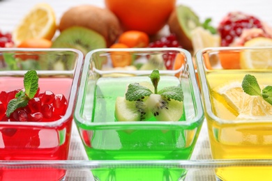 Glass bowls of tasty jelly desserts in tray, closeup