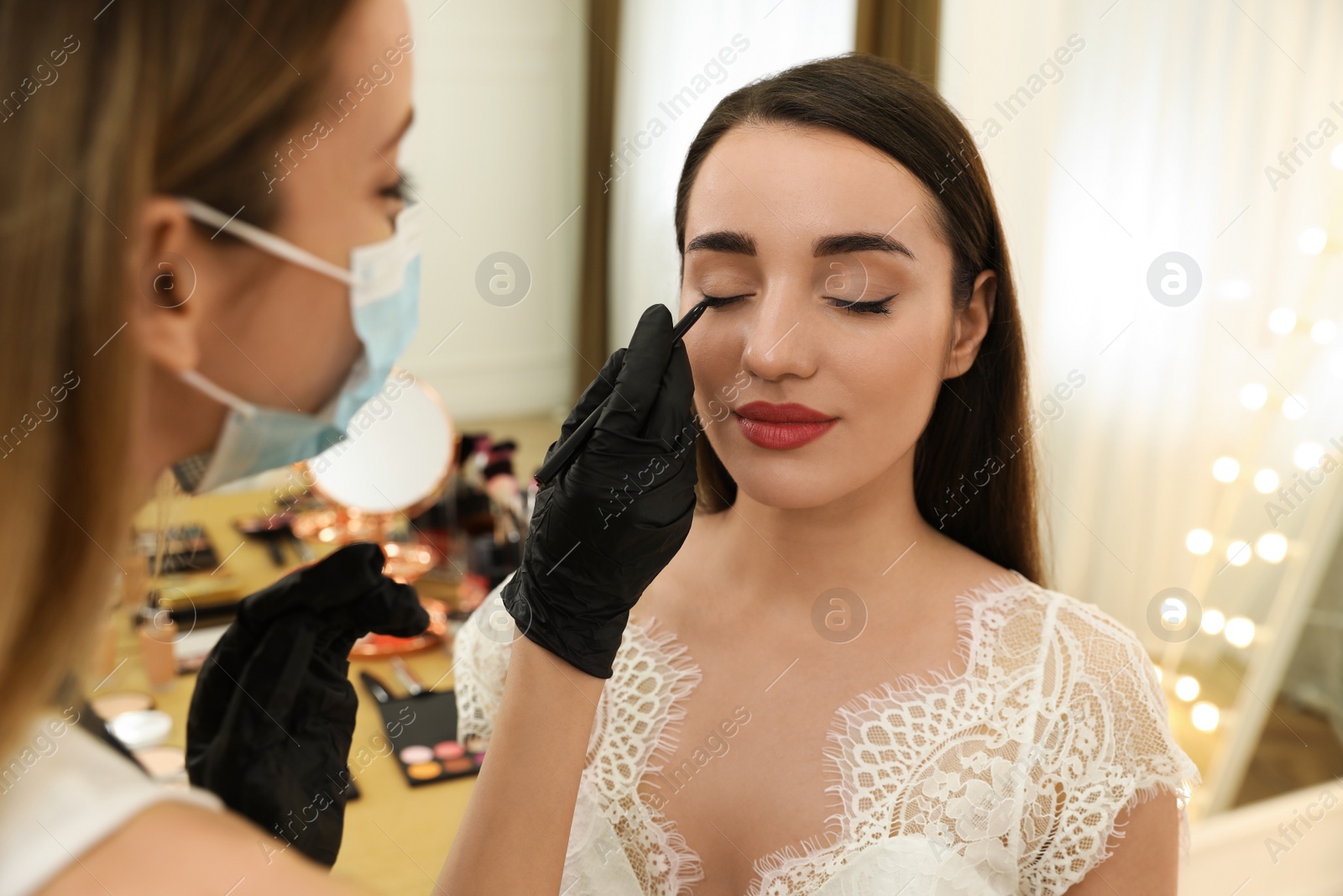 Photo of Professional makeup artist working with client in salon. Beauty services during Coronavirus quarantine