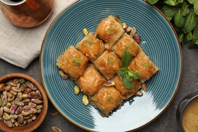 Delicious baklava with pistachios, nuts, mint and hot coffee on grey table, flat lay