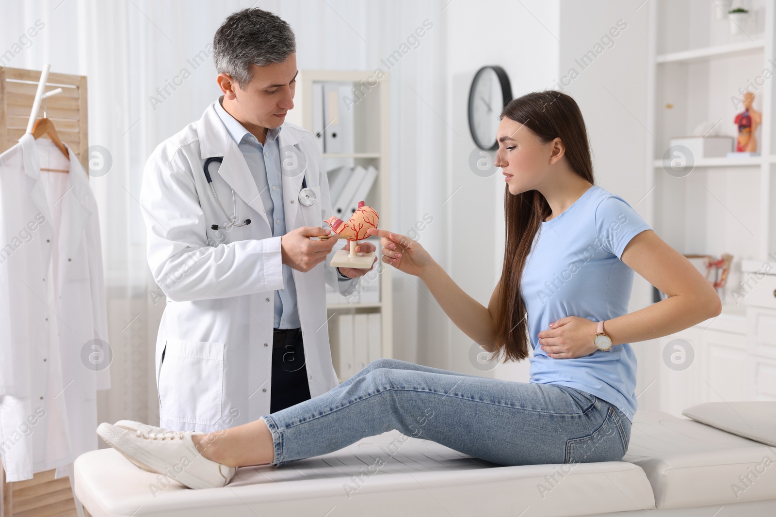 Photo of Gastroenterologist with human stomach model consulting patient in clinic