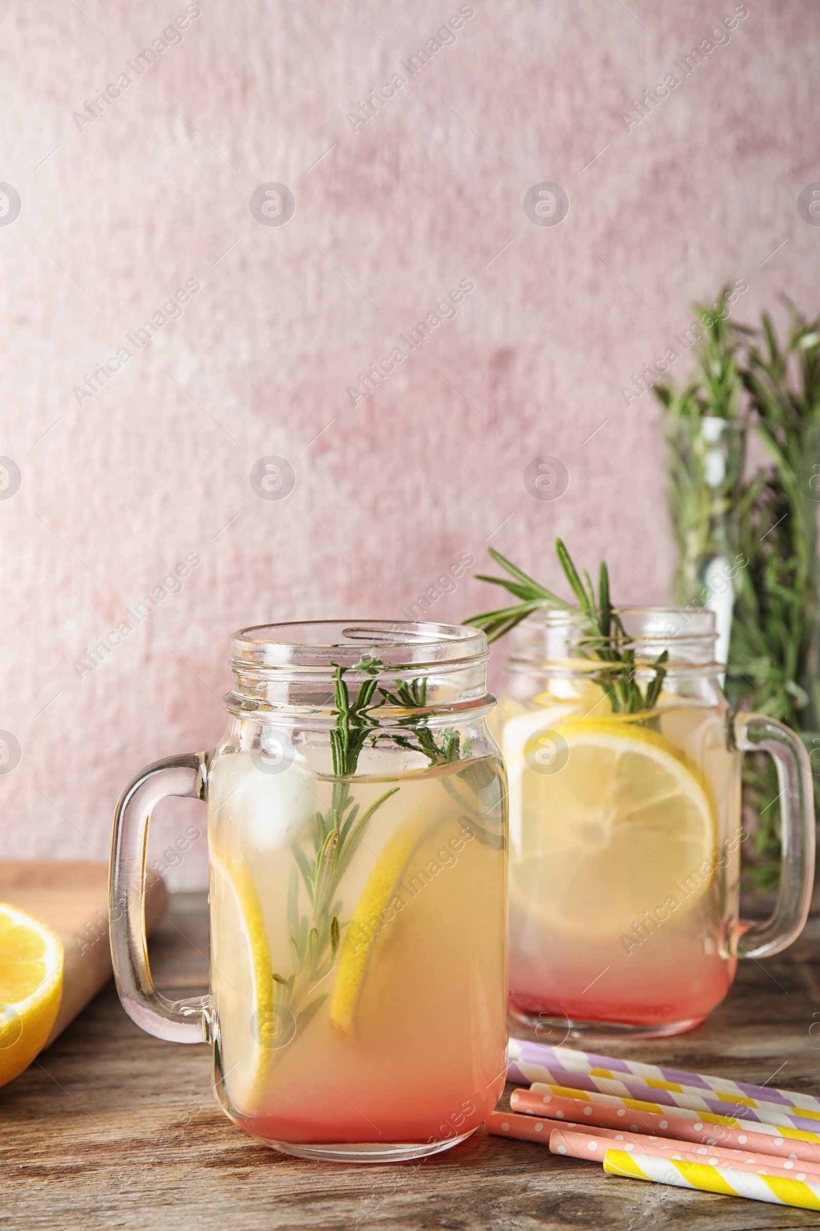Photo of Refreshing lemon cocktail with rosemary in mason jars on table