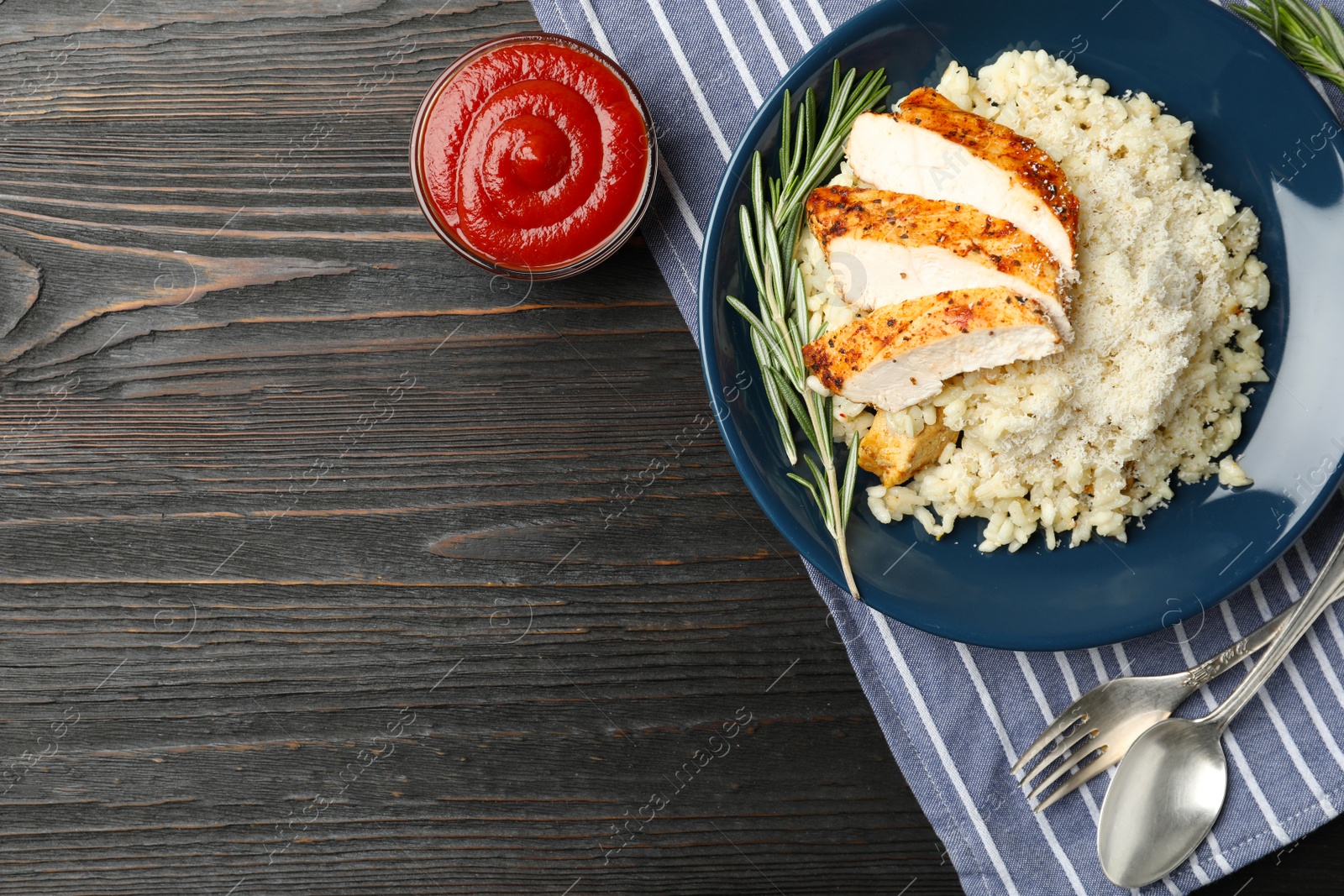 Photo of Delicious chicken risotto served on black wooden table, flat lay. Space for text