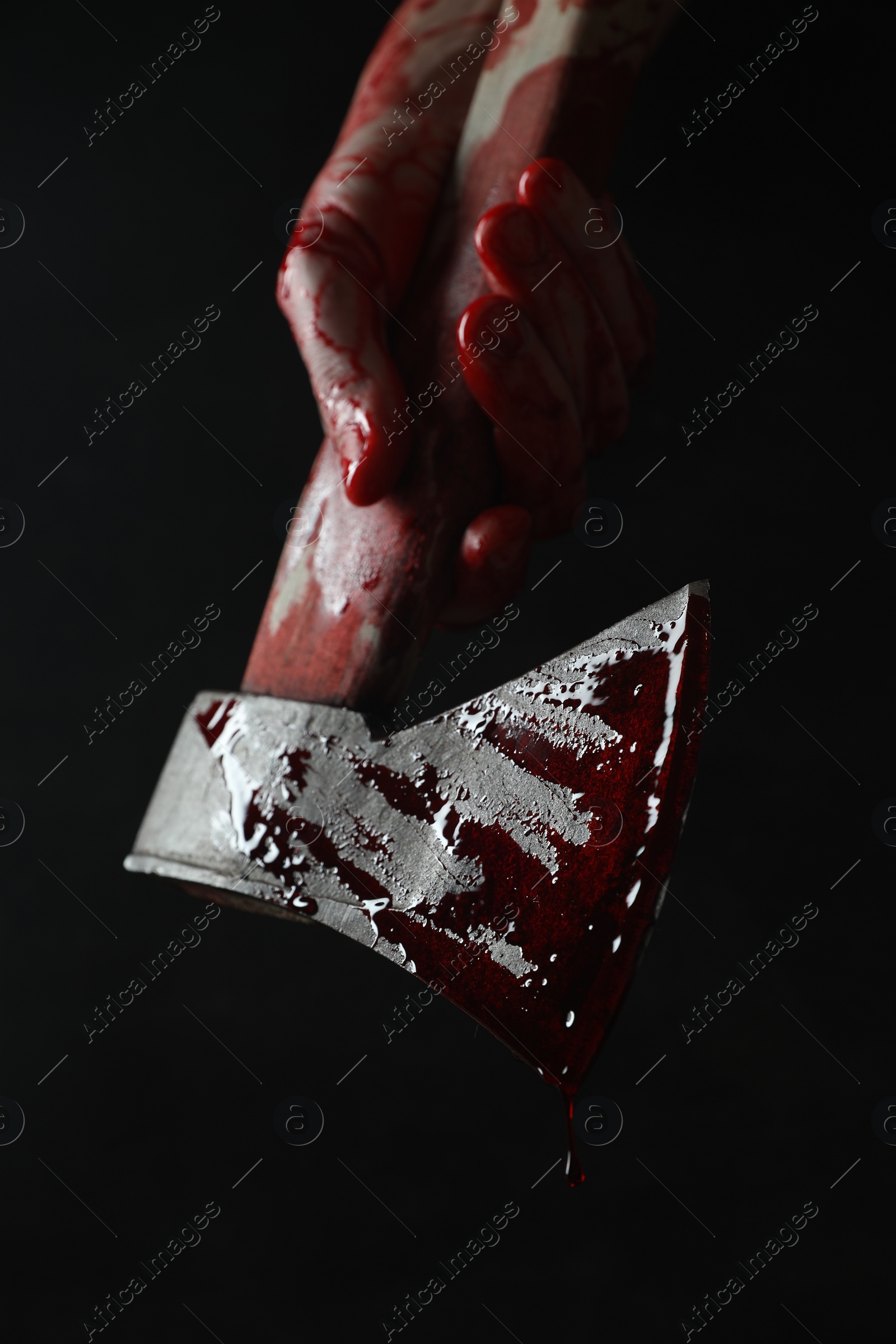 Photo of Man holding bloody axe on black background, closeup