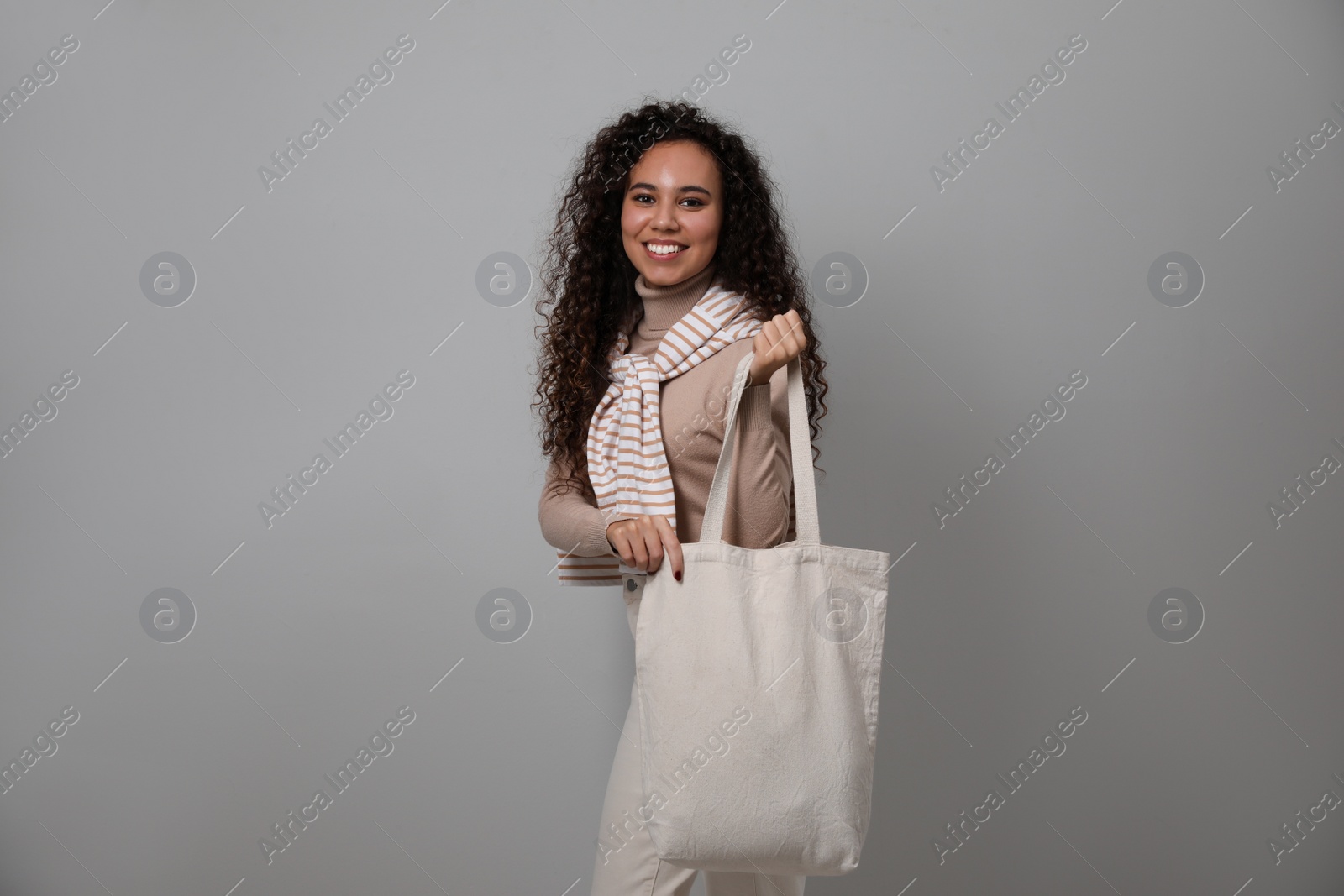 Photo of Happy African-American woman with eco bag on grey background