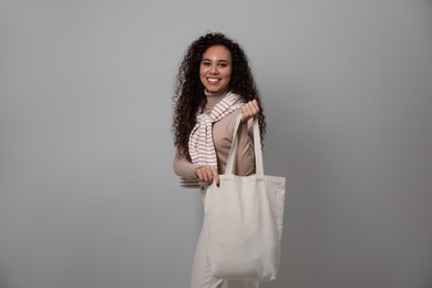 Happy African-American woman with eco bag on grey background