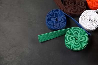 Photo of Colorful karate belts on gray background, flat lay. Space for text