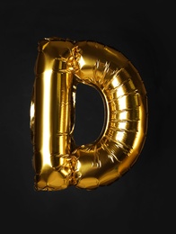 Golden letter D balloon on black background