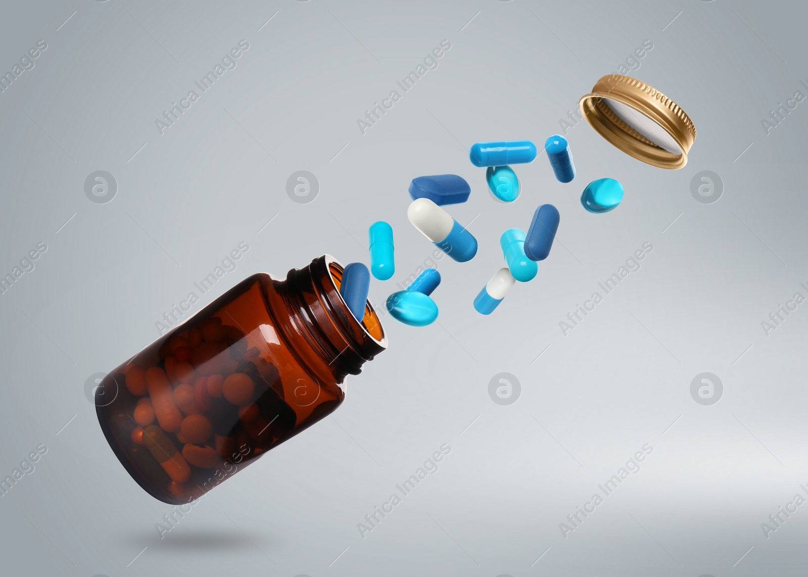 Image of Many different colorful pills bursting out of bottle on light grey background