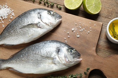 Raw dorada fish on wooden table, flat lay