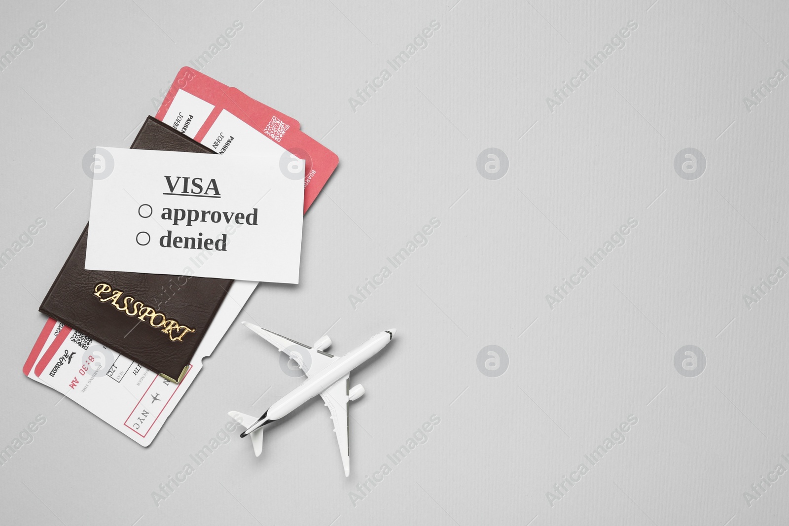 Photo of Flat lay composition with passport, toy plane and tickets on light grey background, space for text. Visa receiving