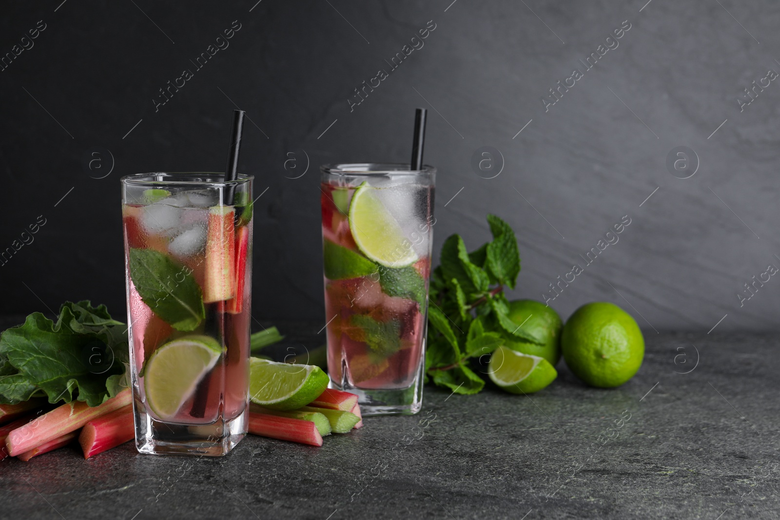 Photo of Tasty rhubarb cocktail with lime on black table, space for text